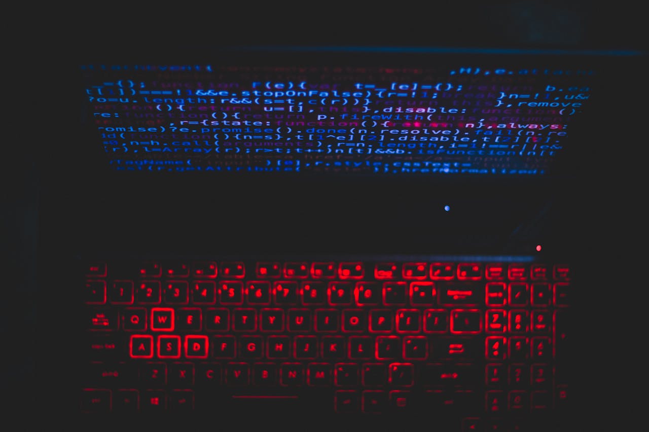 Servicios Dark-themed laptop setup with a red glowing keyboard and code on screen, ideal for tech enthusiasts.