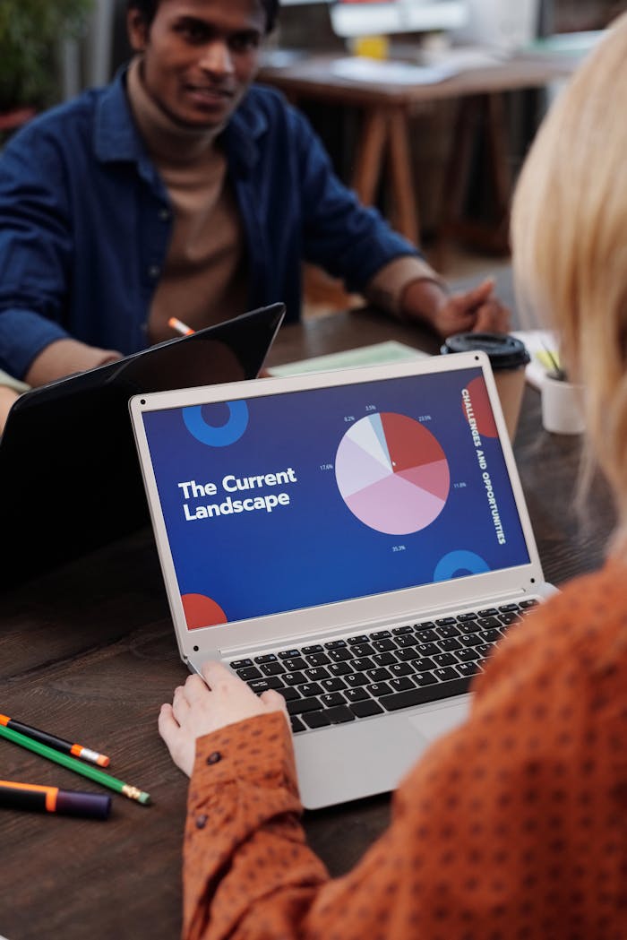 Servicios Team in office discussing a business presentation displayed on a laptop screen.